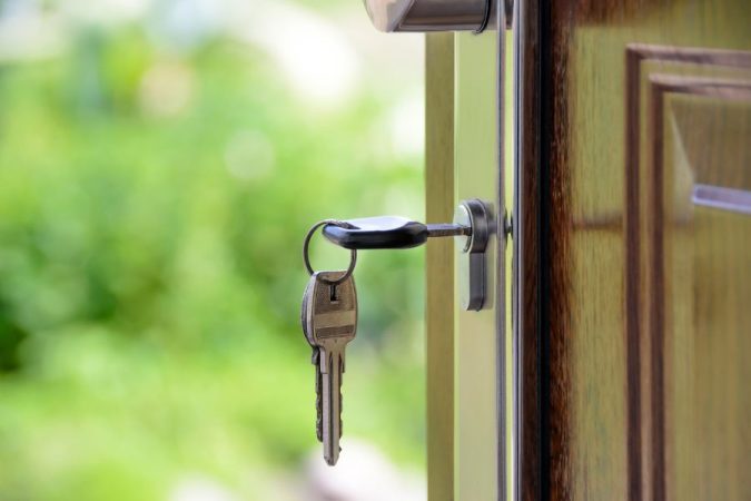 Un trousseau pend à une porte en bois, illustrant le problème d'une clé double coincée dans la serrure.   
